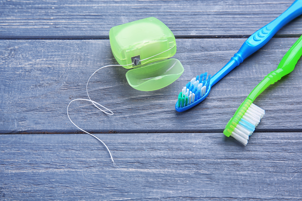 An image of two toothbrushes and floss